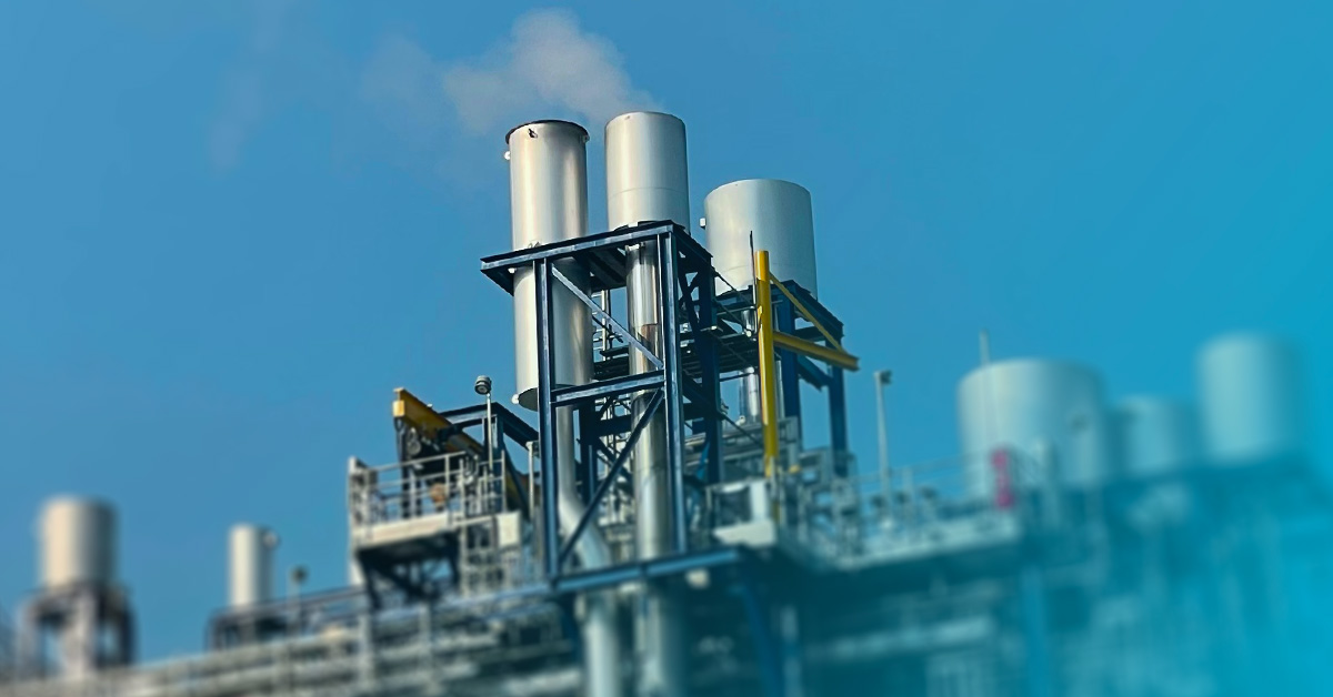 Picture of a power plant releasing water vapour against blue sky.