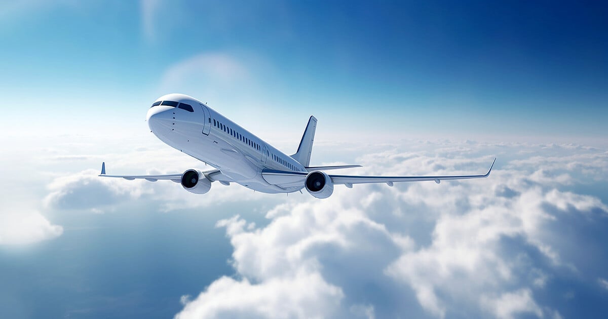 Airplane flying over clouds in a blue sky.