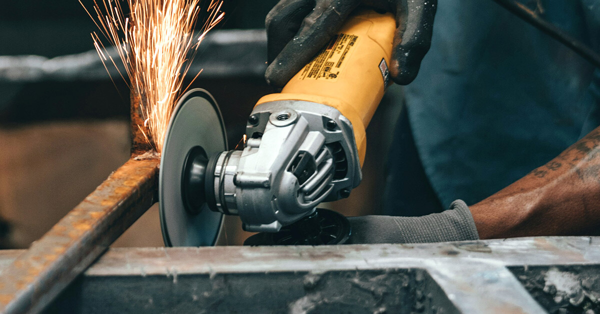 Worker grinding metal with a grinding wheel.