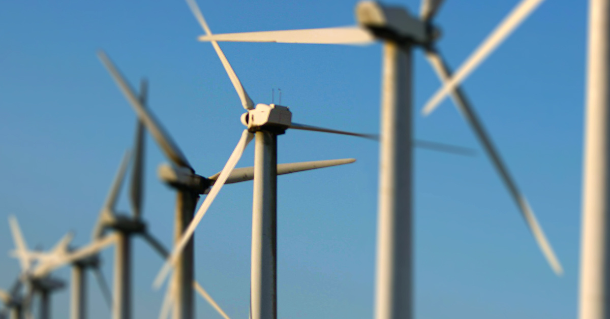 Line of wind blades against blue sky