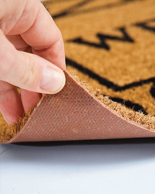 Hand lifting a padded backed flooring with carpet on top.